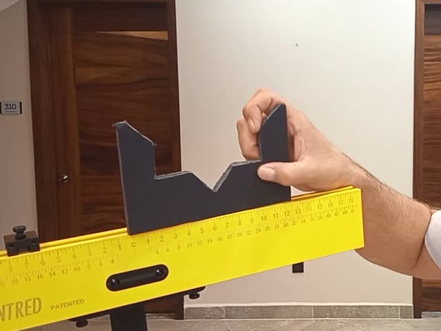 A dark custom jig cut to a sign's shape, fitted to the end stops