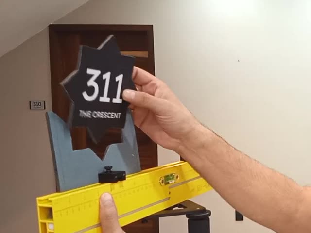 A star-shaped room 311 sign held up to the jig on the tool